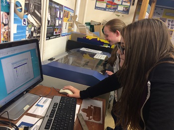 Meg and Cate cutting out a wheel template on the lazer cutter 350 pixels